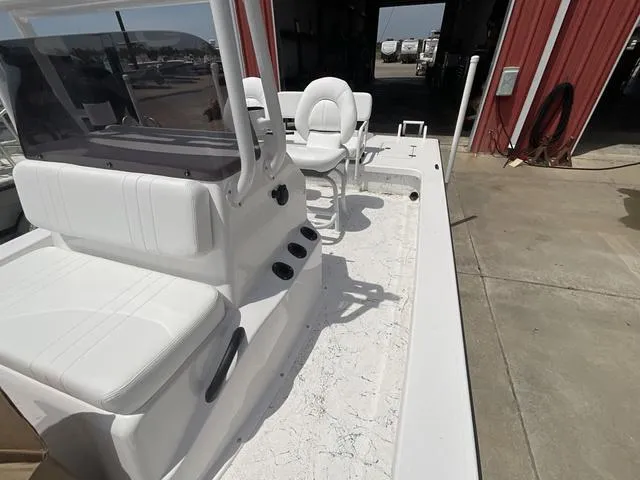 Slide: The Image of 2025 Majek 2206 Illusion boat interior with white seating and console, parked near a red building. - 10