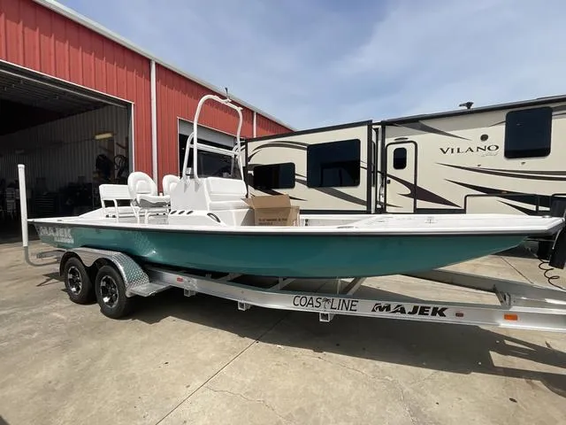 Slide: The Image of 2025 Majek 2206 Illusion boat on trailer, parked near red building and RV. - 3