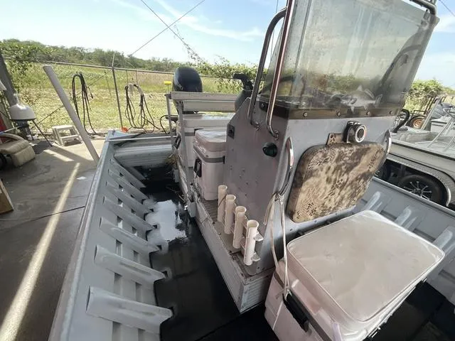 Slide: The Image of 2000 Alumacraft boat interior with steering console and rod holders, parked outdoors. - 9