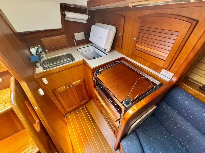 Slide: The Image of 2007 Sabre Spirit yacht interior with wooden cabinetry, compact kitchen, and seating area. - 19