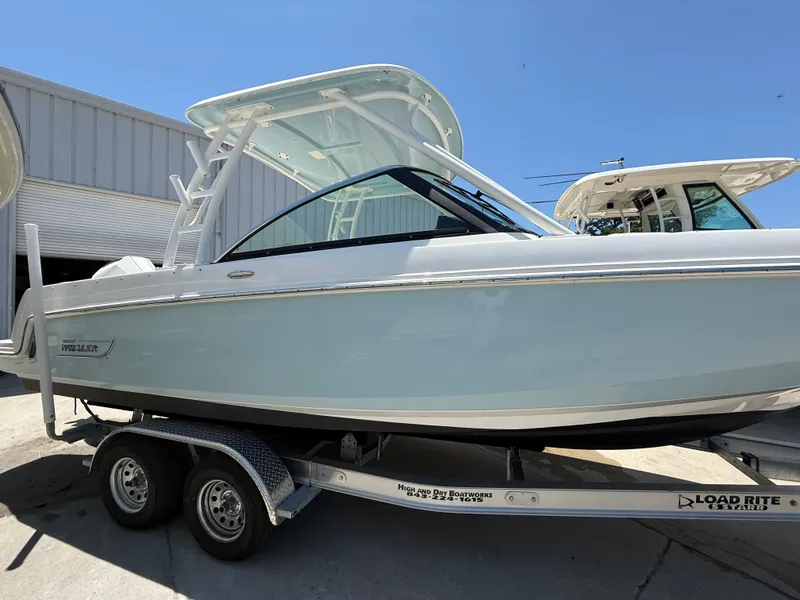 Slide: The Image of 2020 Boston Whaler 230 Vantage boat on trailer, parked outdoors under clear blue sky. - 2
