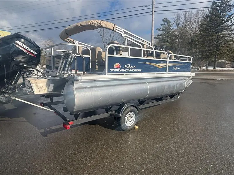 Slide: The Image of 2025 Sun Tracker BB 18 DLX pontoon boat on trailer, parked outdoors. - 3