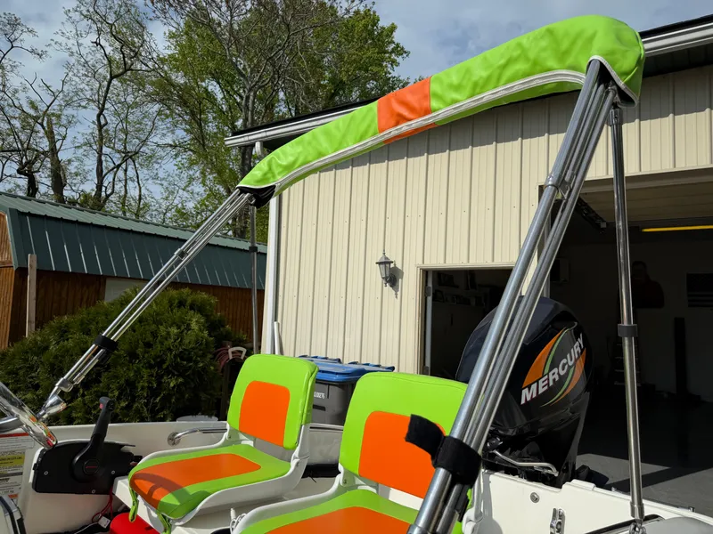 Slide: The Image of 2009 Boston Whaler 130 Super Sport with vibrant seats and canopy, parked near a garage. - 10