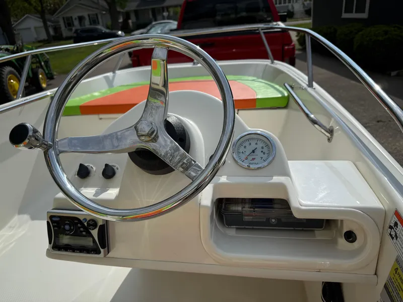 Slide: The Image of 2009 Boston Whaler 130 Super Sport boat dashboard with steering wheel and gauges. - 11