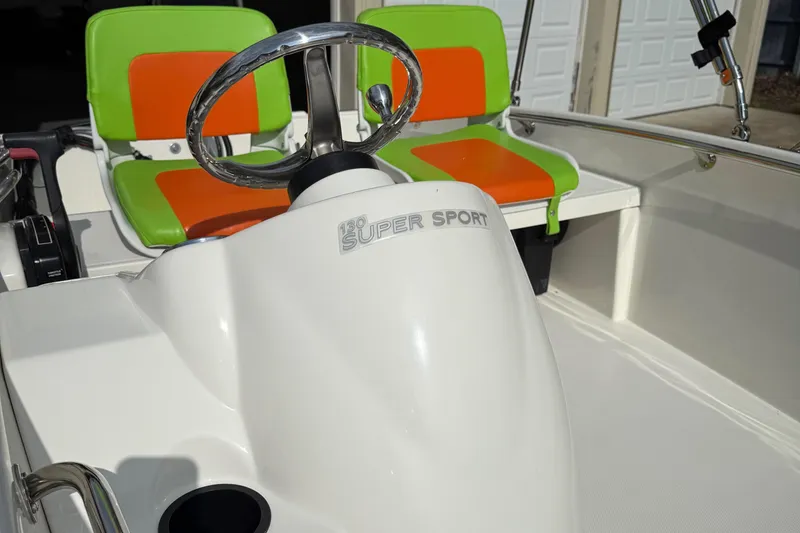 Slide: The Image of 2009 Boston Whaler 130 Super Sport boat with vibrant green and orange seating. - 16