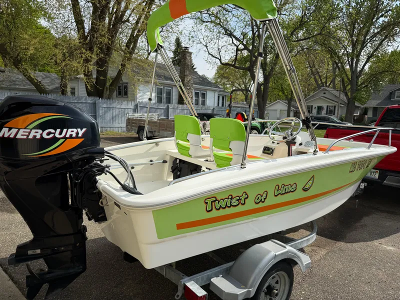 Slide: The Image of 2009 Boston Whaler 130 Super Sport boat with Mercury engine, vibrant green accents, on trailer. - 3