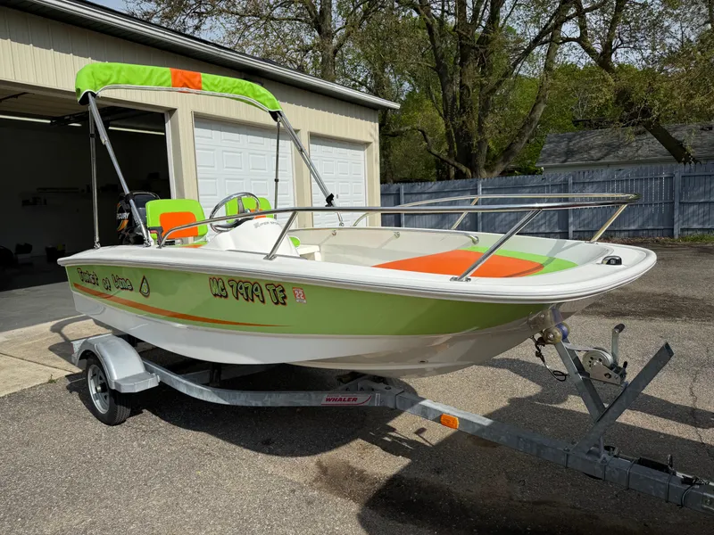 Slide: The Image of 2009 Boston Whaler 130 Super Sport boat with vibrant green and orange accents on a trailer. - 4