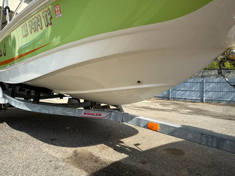 Slide: The Image of 2009 Boston Whaler 130 Super Sport on trailer, green and white hull, parked outdoors. - 5