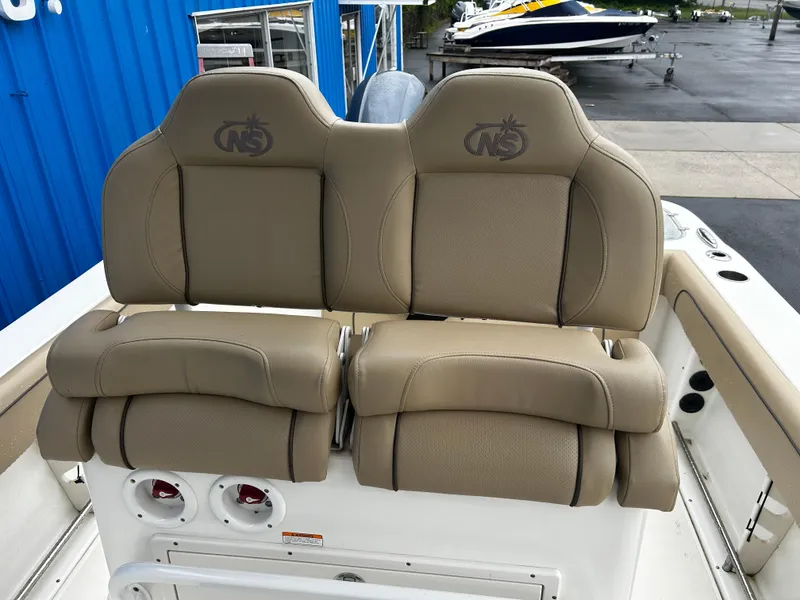 Slide: The Image of 2018 NauticStar 25 XS Offshore boat seats, tan upholstery, dual seating, outdoor setting. - 16