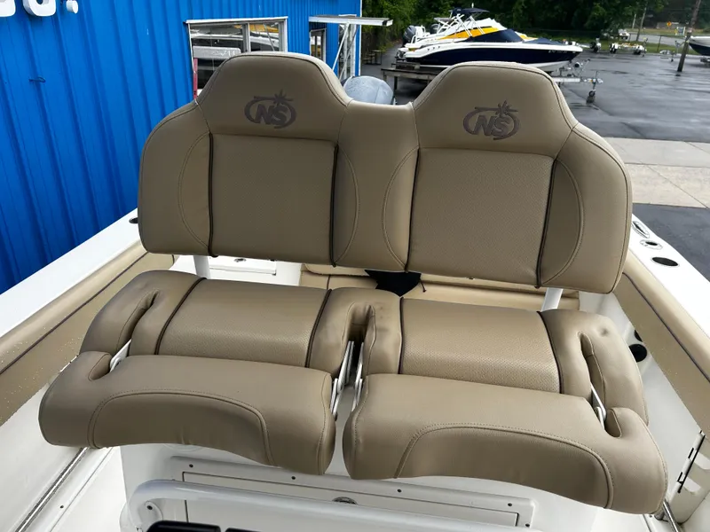 Slide: The Image of 2018 NauticStar 25 XS Offshore boat seats, beige upholstery, outdoor setting. - 17