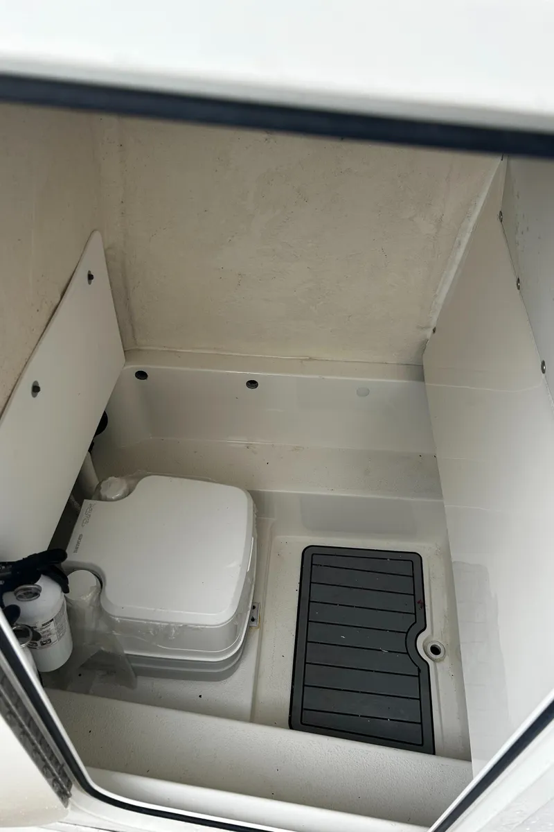 Slide: The Image of 2018 NauticStar 25 XS Offshore boat interior with compact toilet and storage area. - 26