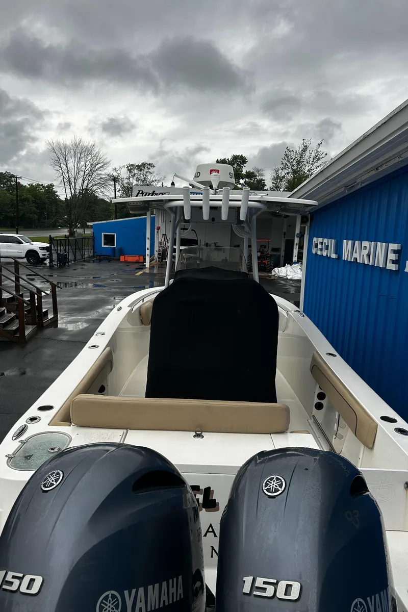 Slide: The Image of 2018 NauticStar 25 XS Offshore boat with twin Yamaha 150 engines, docked near a blue building. - 32