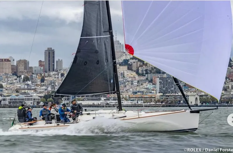 The Image of 2005 J Boats J/100 sailing in a city harbor, crew onboard, with black and white sails. - 0