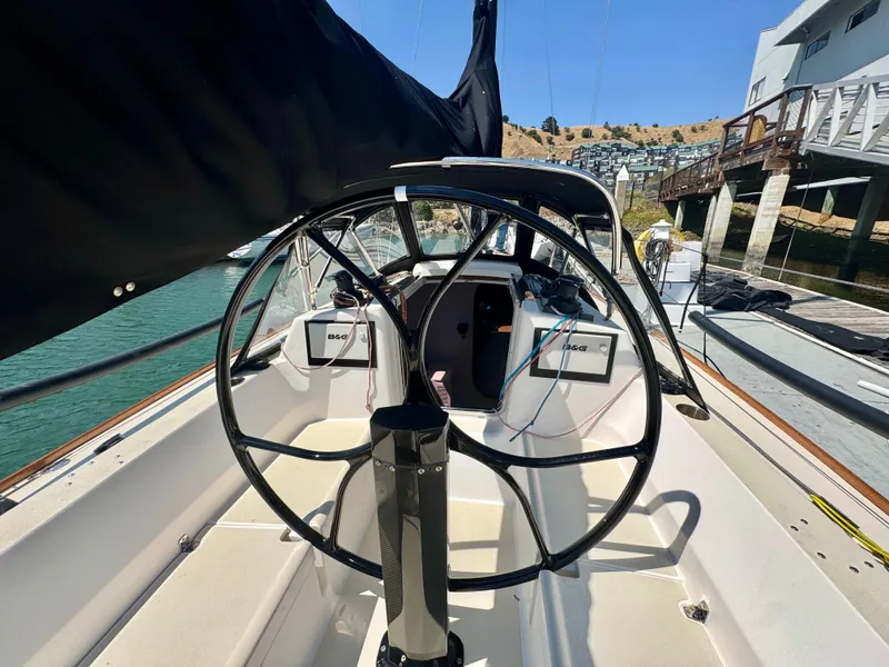 Slide: The Image of 2005 J Boats J/100 sailboat cockpit with steering wheel, docked by waterfront homes. - 16