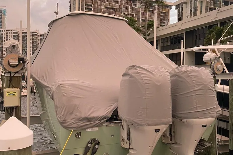 Slide: The Image of Covered 2014 Sailfish 320 CC boat docked with twin engines, urban marina backdrop. - 15