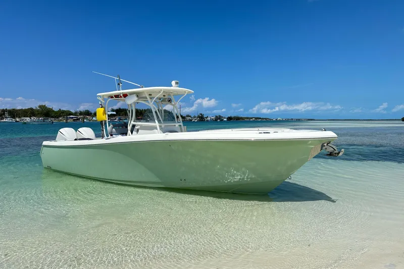 Slide: The Image of 2014 Sailfish 320 CC boat anchored on clear, shallow water with a sunny sky backdrop. - 17