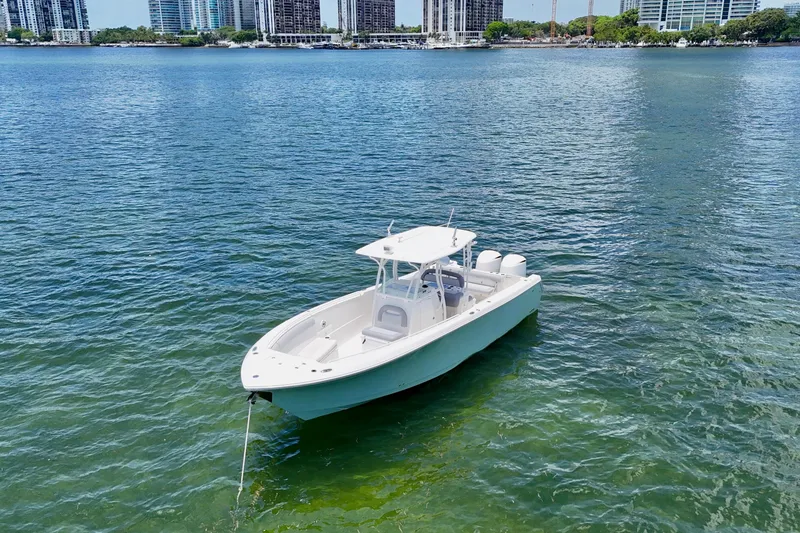 Slide: The Image of 2014 Sailfish 320 CC boat on calm water with city skyline background. - 2