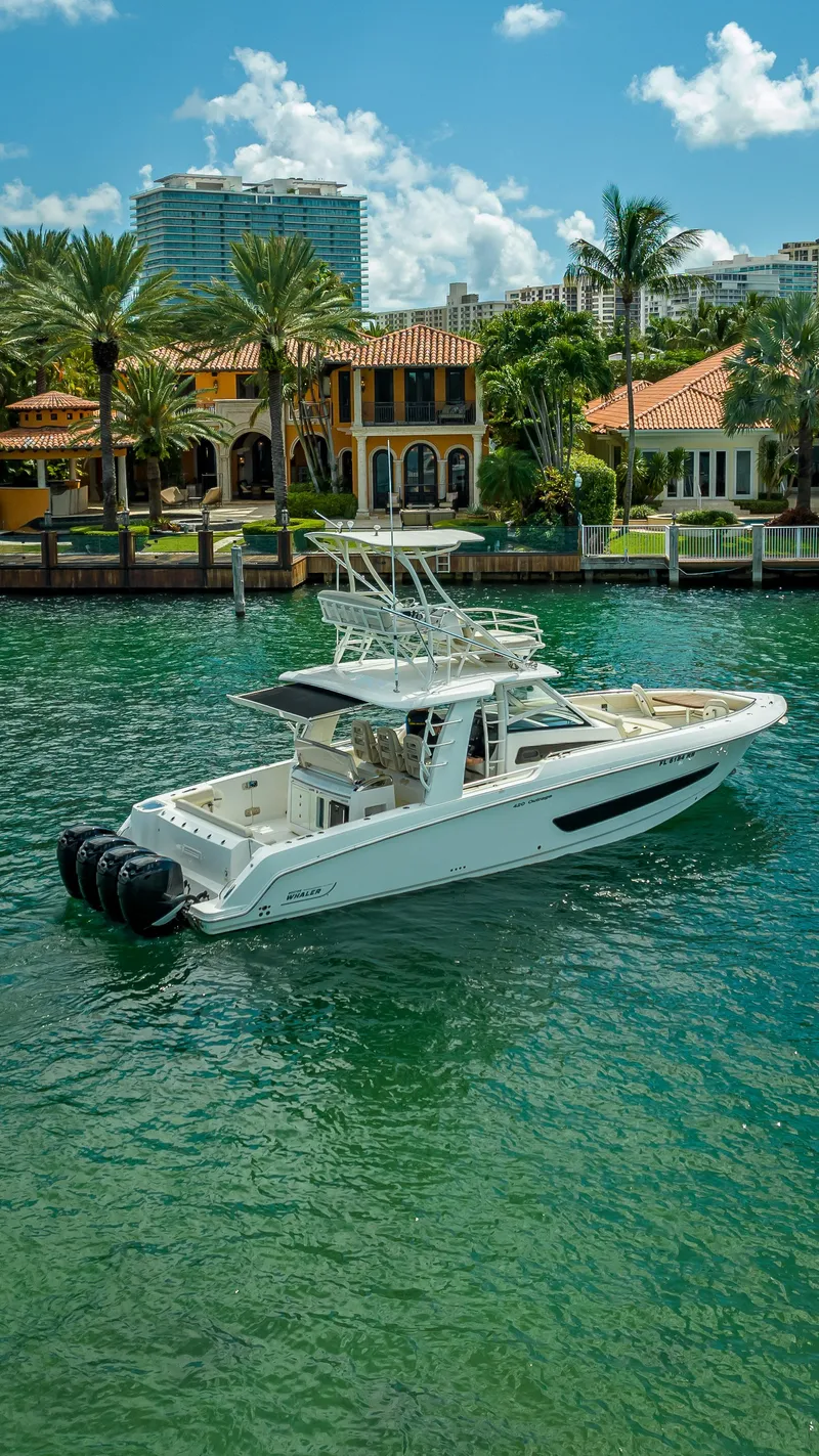 Slide: The Image of 2016 Boston Whaler 420 Outrage boat on clear water near luxury waterfront homes. - 8