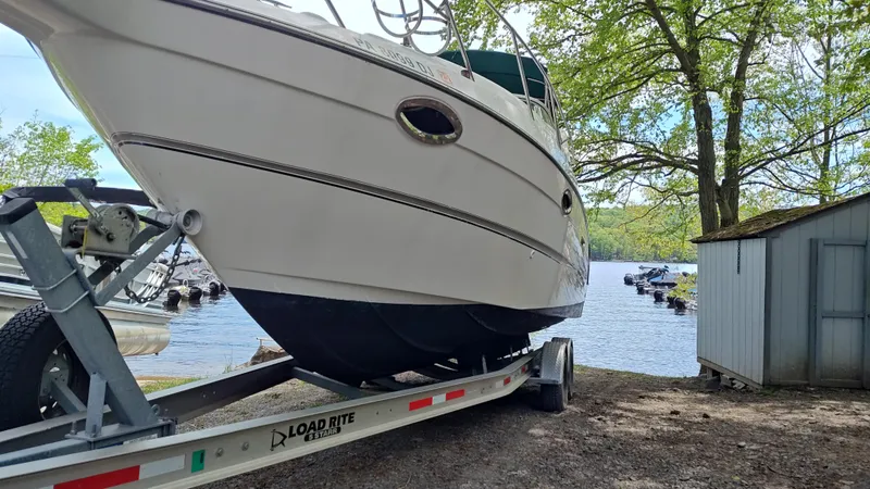 Slide: The Image of 2000 Maxum 2800 SCR boat on trailer near lake, surrounded by trees and shed. - 12