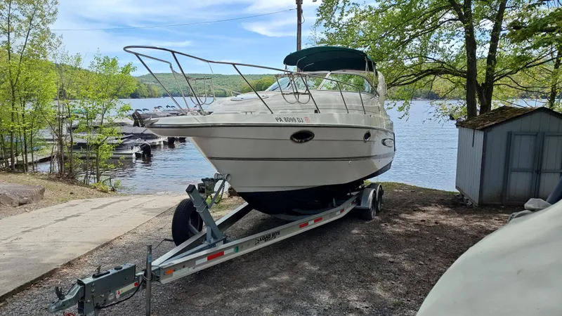 Slide: The Image of 2000 Maxum 2800 SCR boat on trailer by a lakeside with trees and shed. - 23