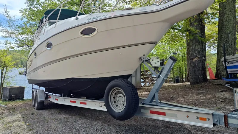 Slide: The Image of 2000 Maxum 2800 SCR boat on trailer near a lake, surrounded by trees. - 24