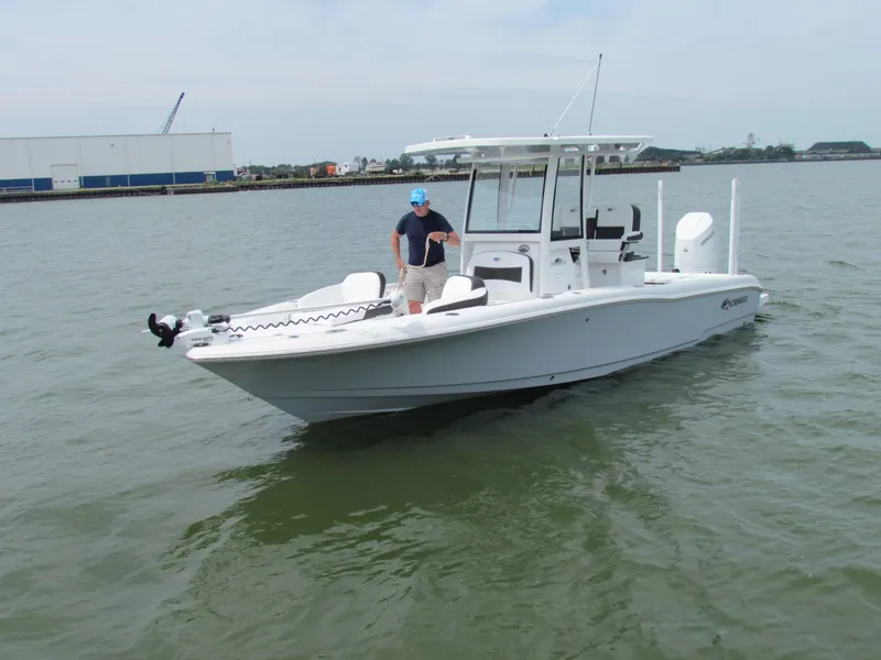 Slide: The Image of 2024 Crevalle 26 HCO boat on water with person standing at helm. - 14