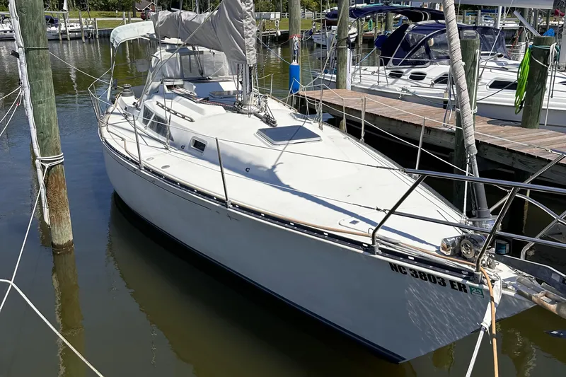 The Image of 1987 C&C 34 sailboat docked in marina, white hull, calm water, sunny day. - 0