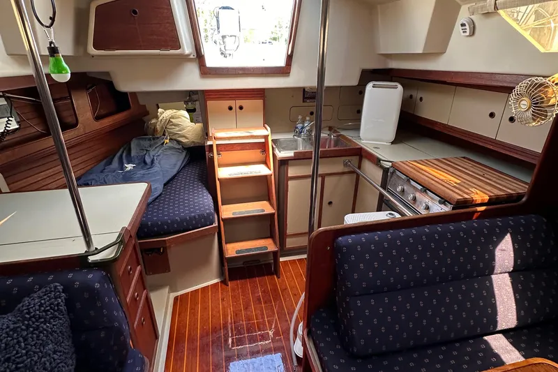 Slide: The Image of Interior of 1987 C&C 34 sailboat with cozy seating, kitchenette, and wooden flooring. - 12