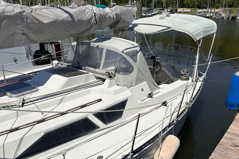 Slide: The Image of 1987 C&C 34 sailboat docked at marina, featuring covered cockpit and sleek design. - 2