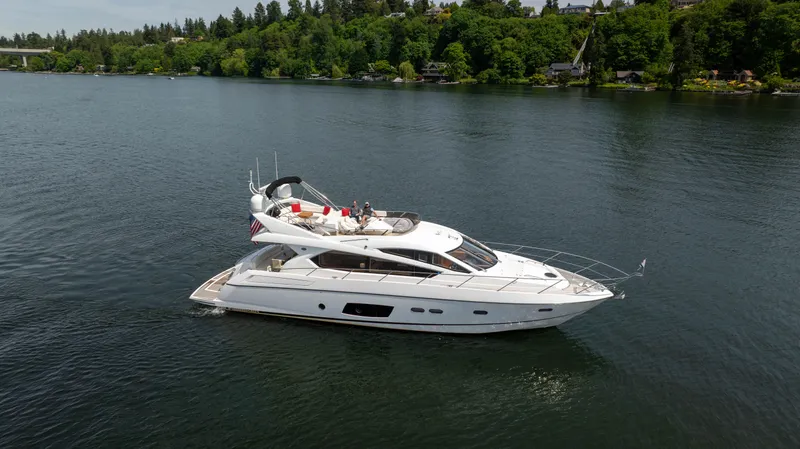 Slide: The Image of 2012 Sunseeker Manhattan 63 yacht cruising on a serene lake with lush green surroundings. - 3