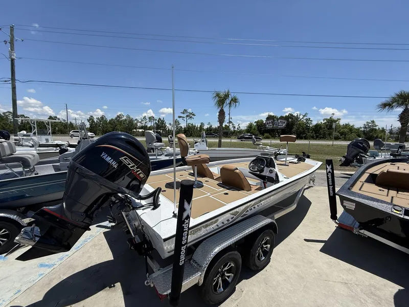 Slide: The Image of 2025 Xpress Hyper-Lift Bass Series boat with Yamaha engine, parked outdoors under clear blue sky. - 6