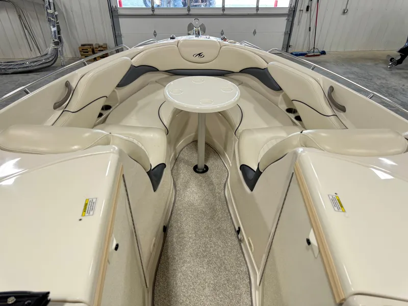 Slide: The Image of 2007 Monterey 298 boat interior with beige seating and a central table in a garage. - 12