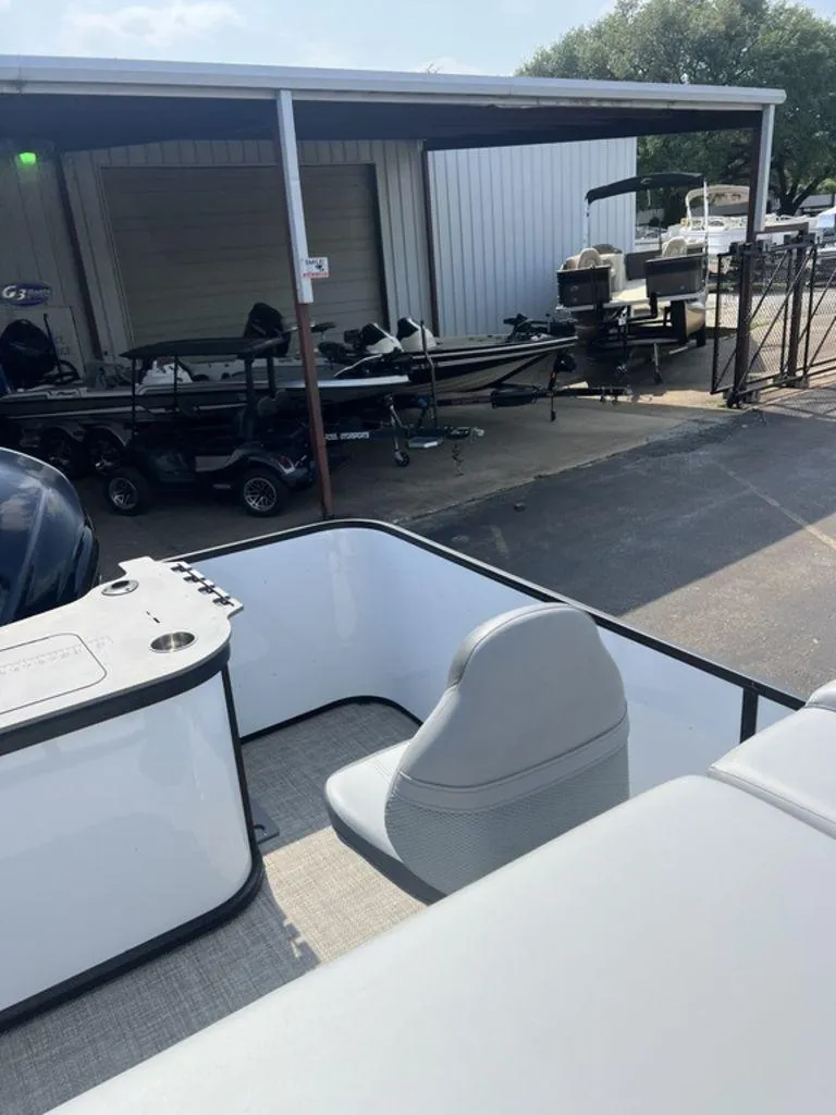 Slide: The Image of 2025 SunCatcher Fusion 322 FC boat interior with seating, parked near storage facility. - 24