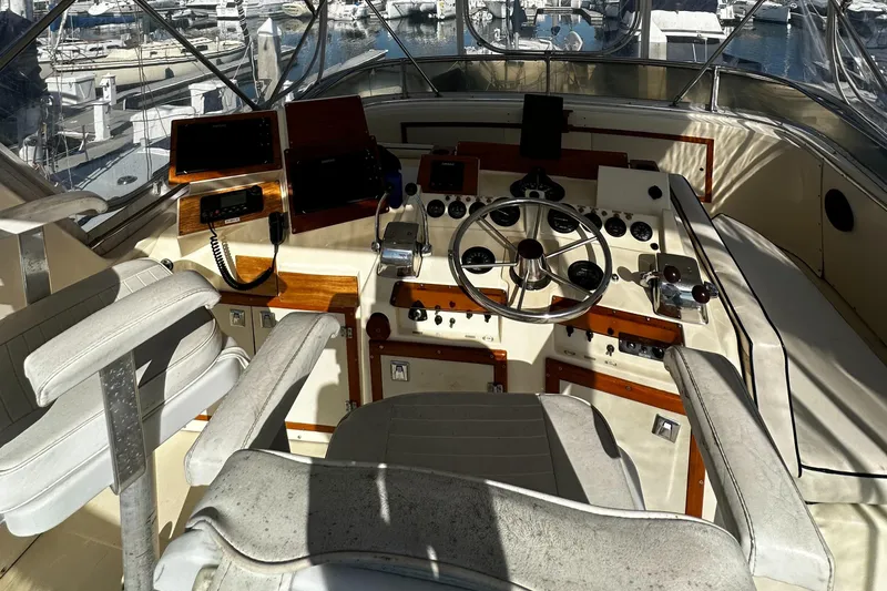 Slide: The Image of 1985 Chris-Craft 382 Commander helm with vintage controls and seating, docked at a marina. - 10