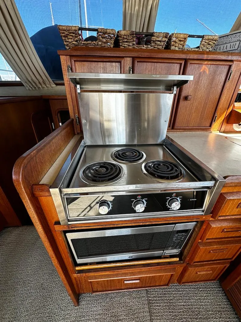 Slide: The Image of 1985 Chris-Craft 382 Commander yacht kitchen with stove and oven, wooden cabinetry, and countertop. - 14