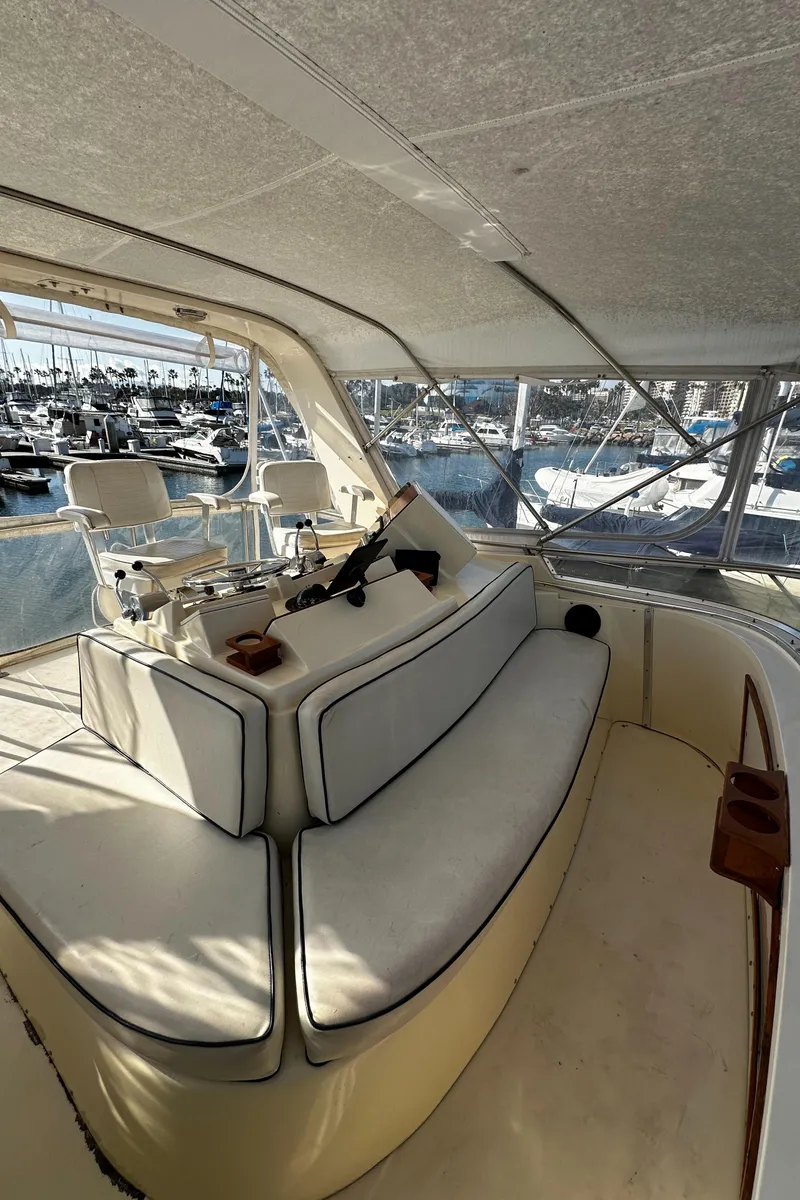 Slide: The Image of 1985 Chris-Craft 382 Commander yacht interior with cushioned seating and marina view. - 7