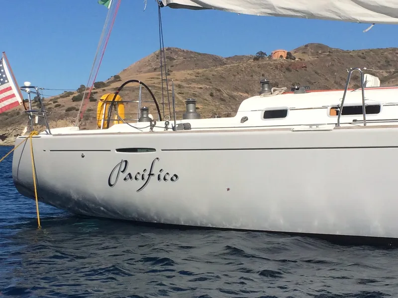 Slide: The Image of 2005 Beneteau First 44.7 sailboat named "Pacifico" on calm waters near rocky coastline. - 14