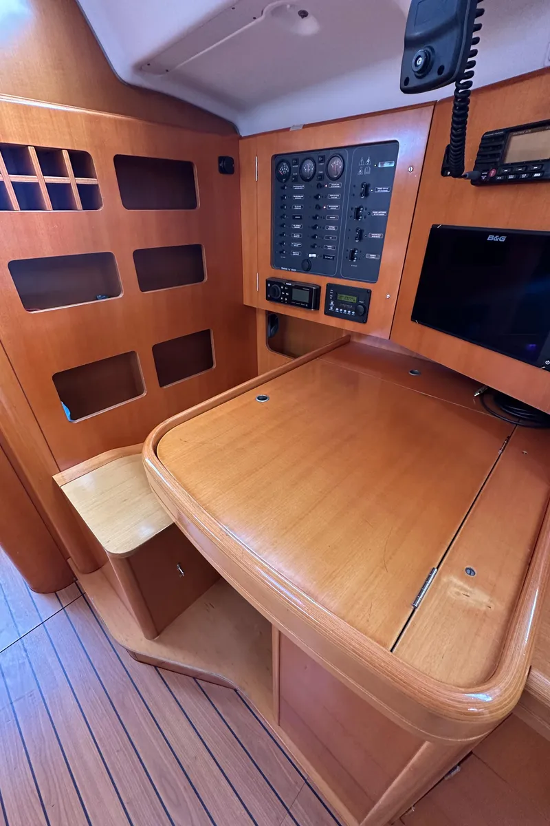 Slide: The Image of Navigation station of 2005 Beneteau First 44.7 yacht with wooden finish and control panel. - 31