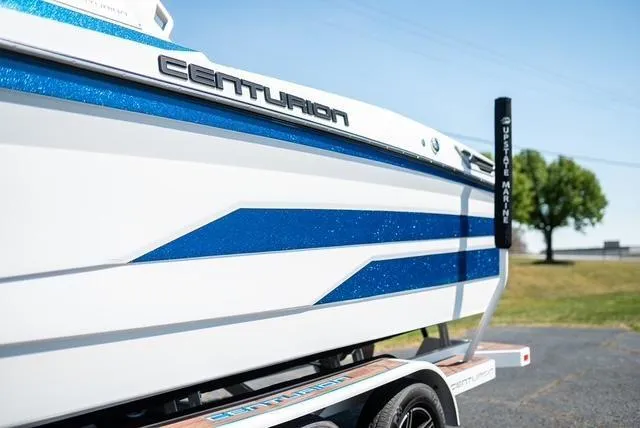 Slide: The Image of 2022 Centurion Ri265 boat with blue accents on a trailer, parked outdoors. - 10