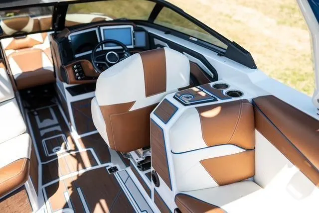 Slide: The Image of 2022 Centurion Ri265 boat interior with brown and white leather seating, modern dashboard, and cup holders. - 17