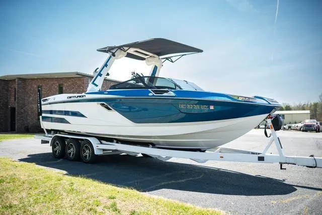 Slide: The Image of 2022 Centurion Ri265 boat on trailer, blue and white design, parked outdoors. - 23