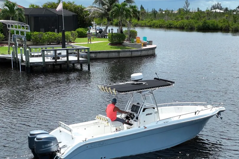 Slide: The Image of A 2007 Century 2600CC boat cruising near a dock with lush greenery and palm trees. - 5