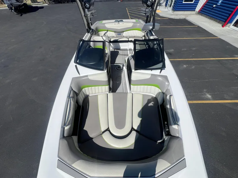 Slide: The Image of 2014 Malibu W22MXZ boat with open windshield and stylish seating in a parking lot. - 17