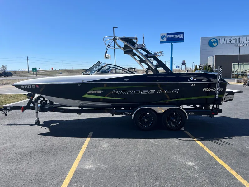 Slide: The Image of 2014 Malibu Wakesetter W22MXZ boat on trailer in parking lot, clear sky background. - 6