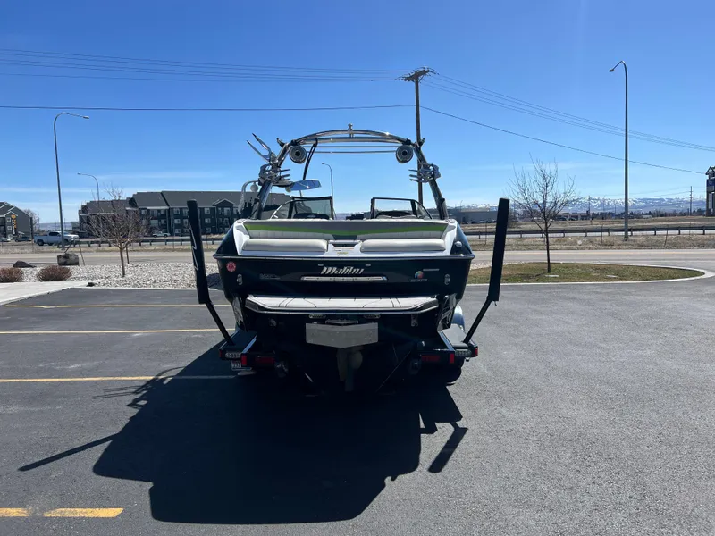 Slide: The Image of 2014 Malibu W22MXZ boat on trailer in parking lot, clear blue sky background. - 8