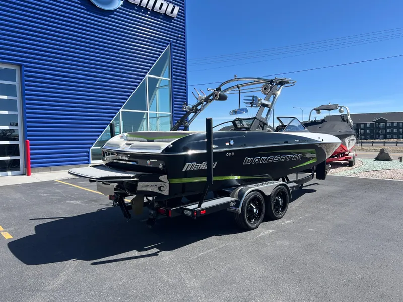 Slide: The Image of 2014 Malibu W22MXZ boat on trailer outside blue building. - 9