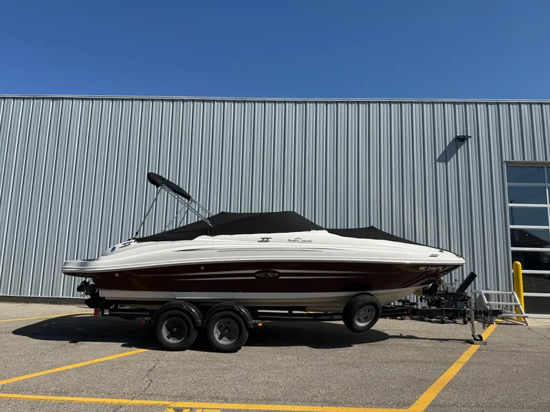 Slide: The Image of 2008 Sea Ray 220 boat on trailer, parked beside a metal building under clear blue sky. - 23