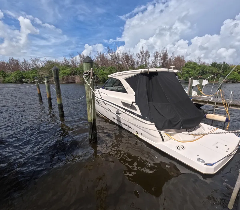 Slide: The Image of 2015 Regal 35 Sport Coupe docked on a sunny day with lush greenery. - 0