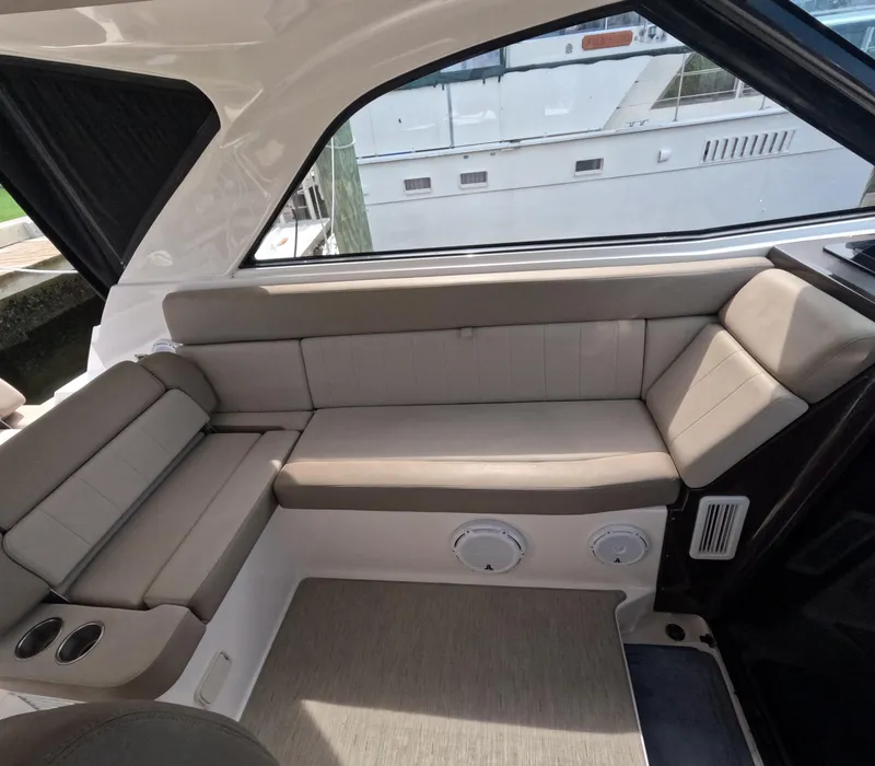 Slide: The Image of 2015 Regal 35 Sport Coupe interior seating area with beige cushions and window view. - 43
