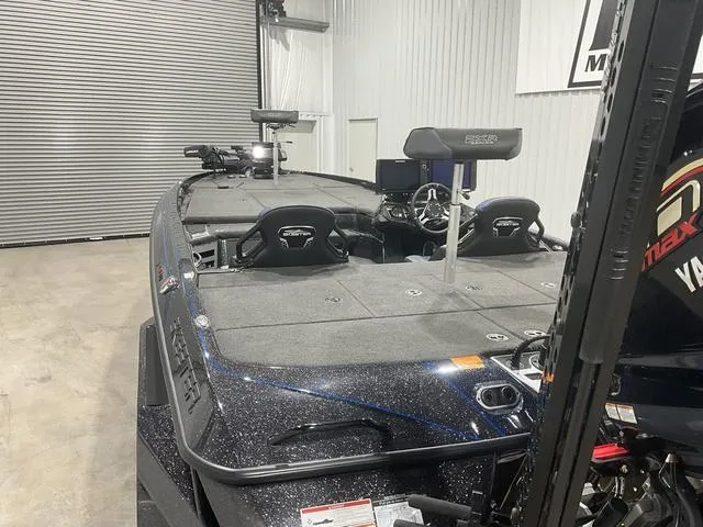 Slide: The Image of 2022 Skeeter FXR21 Select bass boat in a garage, featuring spacious deck and seating. - 12